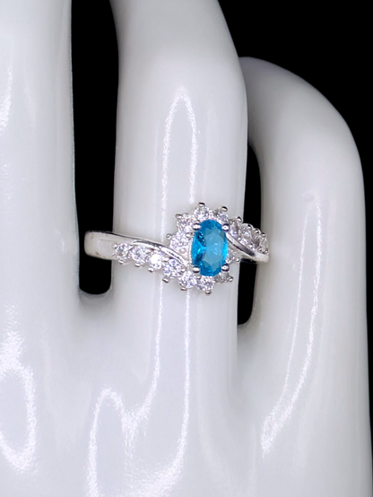 Vintage Inspired Oval Cut Simulated Aquamarine Solitaire with Simulated Diamond Sunburst Crossover Halo Silver Toned Ring