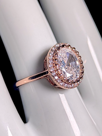 Vintage Inspired Simulated Diamond Solitaire with Simulated Diamond Halo with Asymmetrical Designed Mount Rose Gold Toned Ring