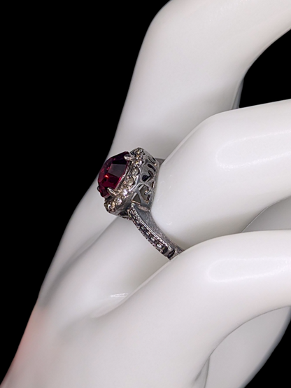 Vintage Inspired Round Single Cut Simulated Ruby Solitaire with Simulated Diamond Halo on Intricate Mount Oxidized Silver Toned Ring