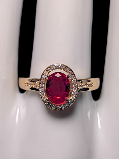 Vintage Inspired Oval Cut Simulated Ruby Solitaire with Simulated Diamond Halo Gold Toned Ring