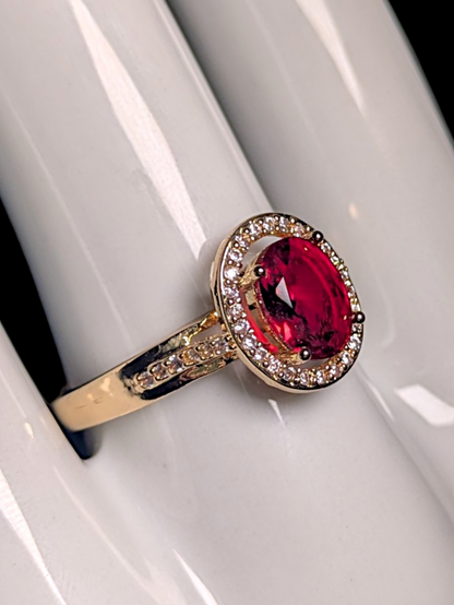 Vintage Inspired Oval Cut Simulated Ruby Solitaire with Simulated Diamond Halo Gold Toned Ring